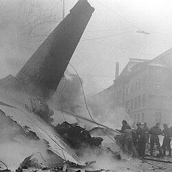 Männer der Flughafenfeuerwehr und der Berufsfeuerwehr gehen gemeinsam mit zwei Schaumrohren am Wrack vor. | Quelle: Archiv BFM