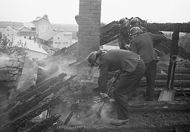 Feuerwehrmänner der BF beim Schuttausgraben im Fehlboden des Dachstuhls auf der Suche nach Brandnestern