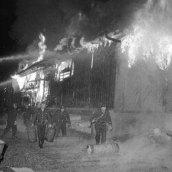 Kräfte der BF und FF bergen Gasflaschen und bringen diese in Sicherheit vor den Flammen